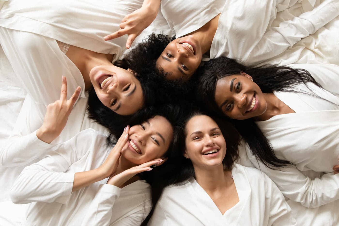 Overhead view of five women lying in a circle, smiling together