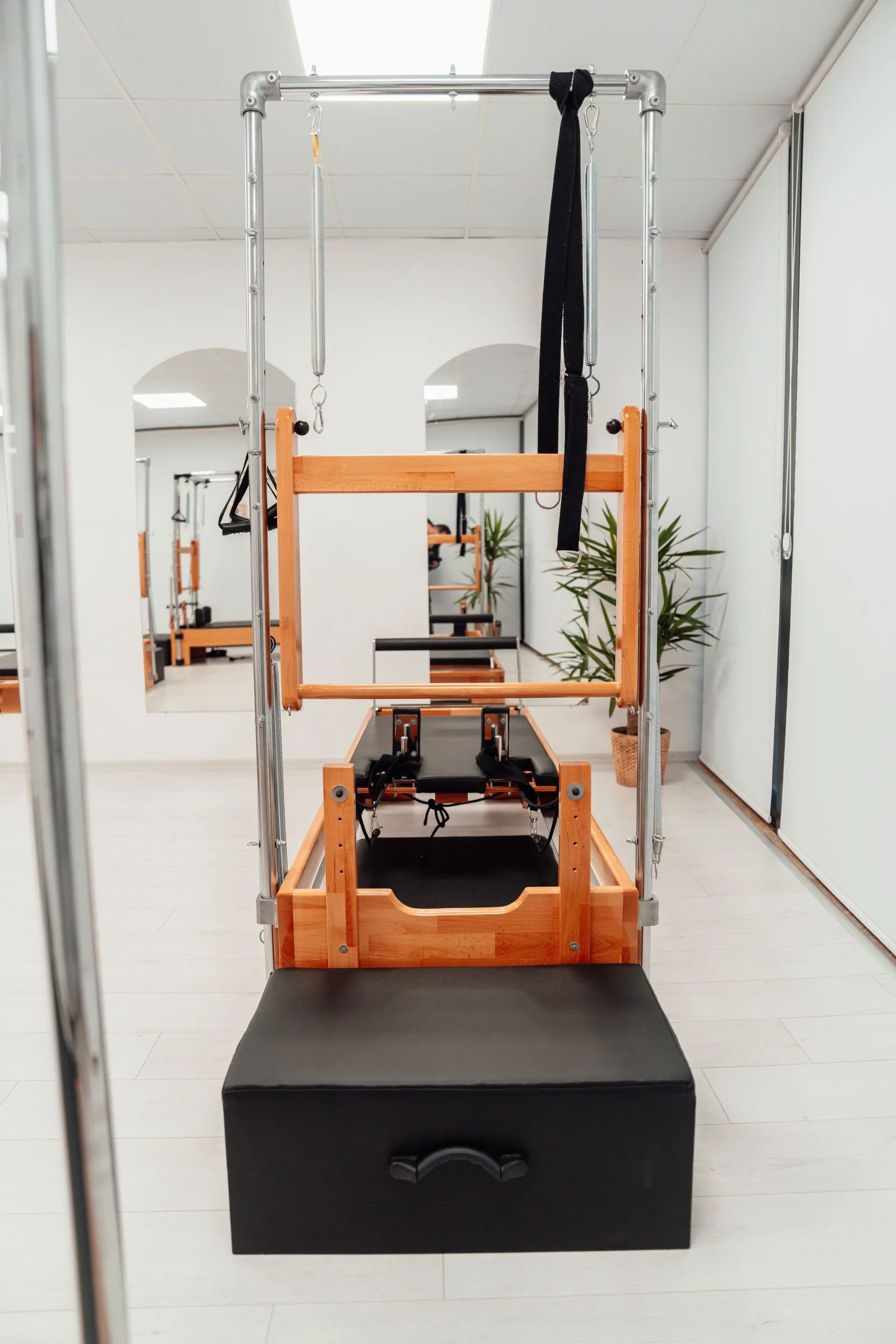 A Pilates reformer and tower machine in a bright studio